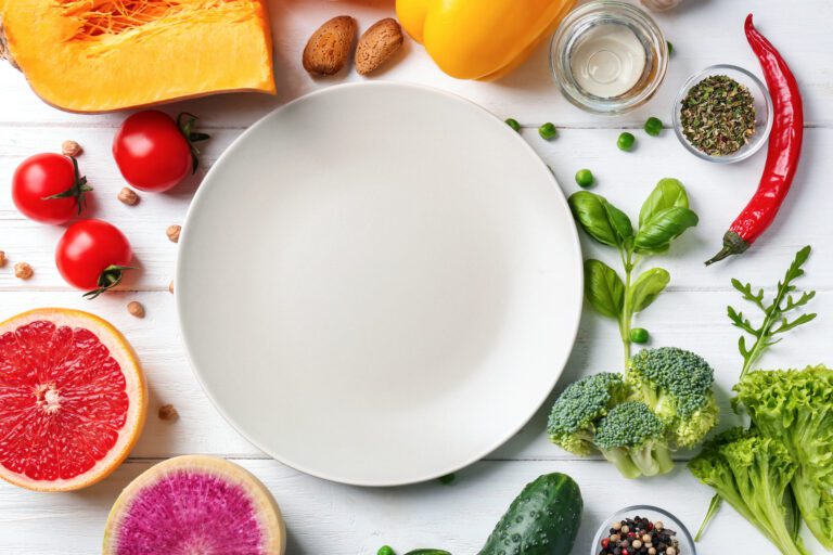 Fresh ingredients for vegetable salad and plate on wooden table